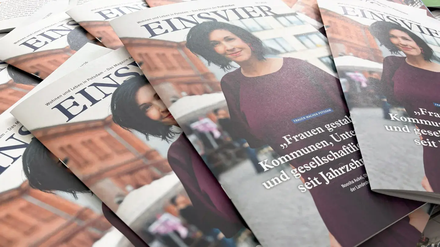 EINSVIER 1-2026 Mehrere Magazine liegen aufgefächert auf einem Tisch. Auf dem Titelbild ist eine Frau mit dunklen Haaren und einem lilafarbenen Kleid zu sehen.