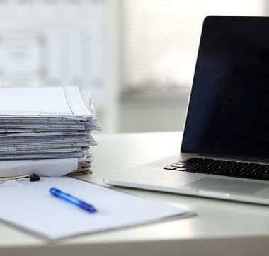Ein Stapel Papier und ein Laptop
