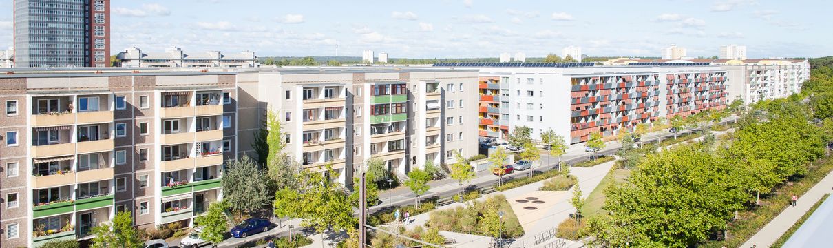 Ansicht über eine Straße mit Parkanlage und Gebäuden am Seitenrand.