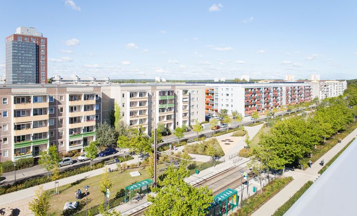 Ansicht über eine Straße mit Parkanlage und Gebäuden am Seitenrand.