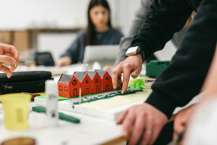 Auf dem Foto sind Schüler und kleine Häusermodelle aus Pappe zu sehen.