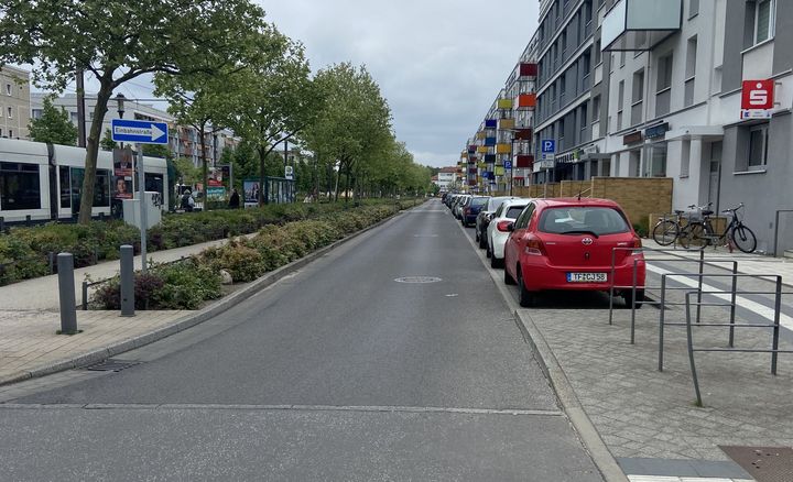 Eine Straße in einem Wohngebiet mit parkenden Autoas am Rand.