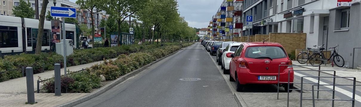 Eine Straße in einem Wohngebiet mit parkenden Autoas am Rand.