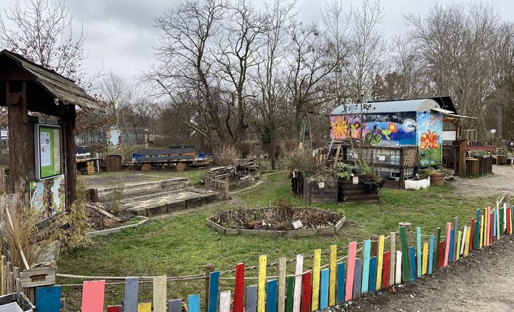 Garten mit einem buntbemalten Holzzaun und Gartenhaus.
