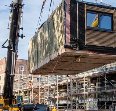 Gebäudeteil, der vor Baustelle mit Hilfe eines Krans in die Luft gehoben wird