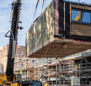 Gebäudeteil, der vor Baustelle mit Hilfe eines Krans in die Luft gehoben wird
