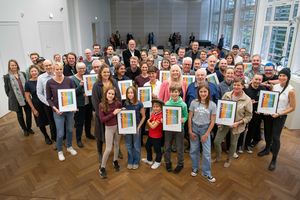 Zahlreiche Menschen mit Urkunden in der Hand lächeln in die Kamera.