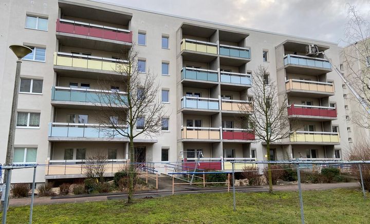 Wohngebäude mit Balkonen und grüner Wiese im Vordergrund.